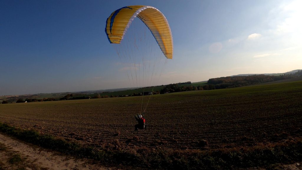 RC-Gleitschirm Phasor 2.3 RAST fliegt im Sonnenuntergang über ein Feld