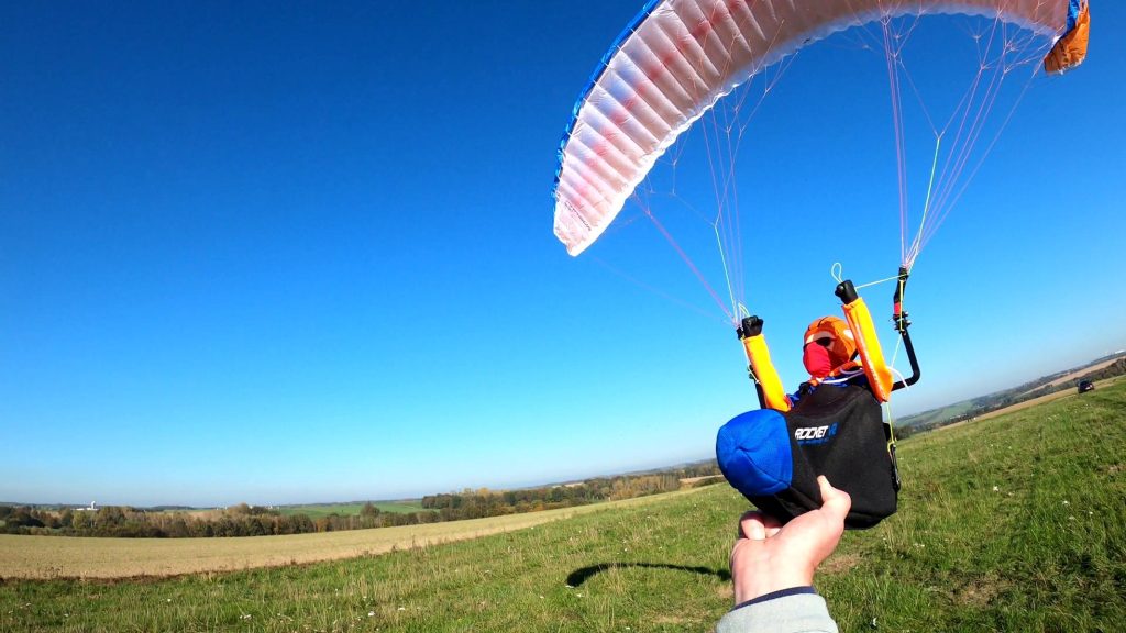 rc-gleitschirm doubleskin phasor2.3 mit liegegurtzeug rocket V2 ist gestartet und hält das liegegurtzeug rocket v2 in der hand