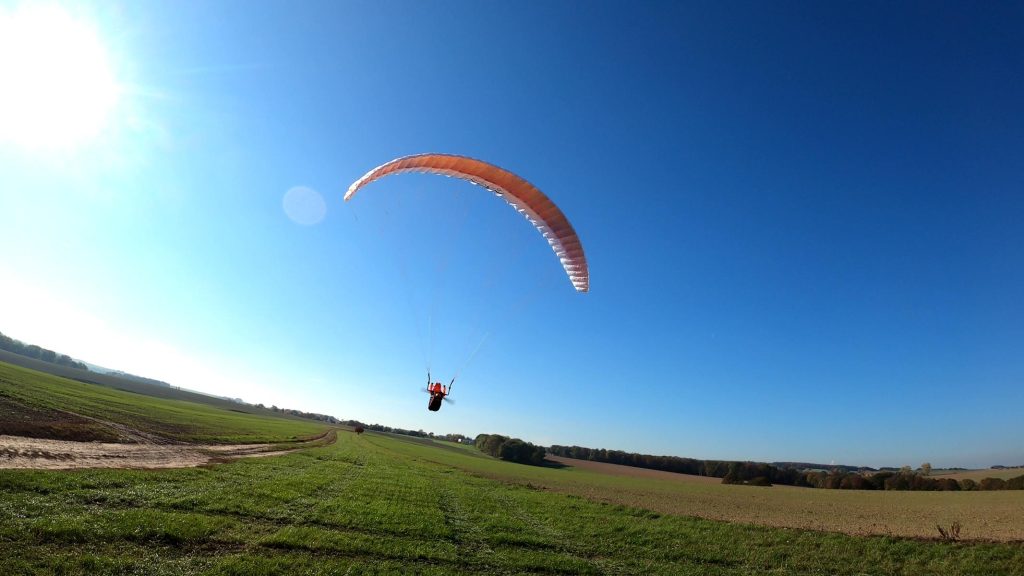 rc-gleitschirm doubleskin phasor2.3 mit liegegurtzeug rocket V2 fliegt über felder mit blauen himmel