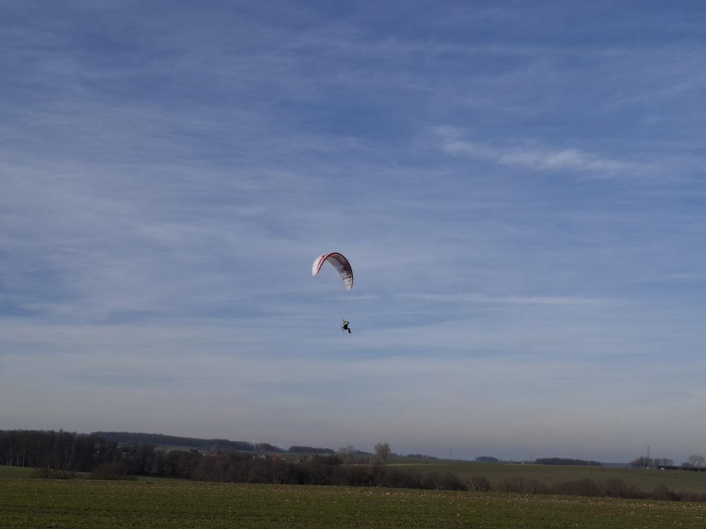 RC-Gleitschirm fliegt am Himmel. Hybrid Stable 2.1 Race RAST fliegt über eine grüne Wiese.