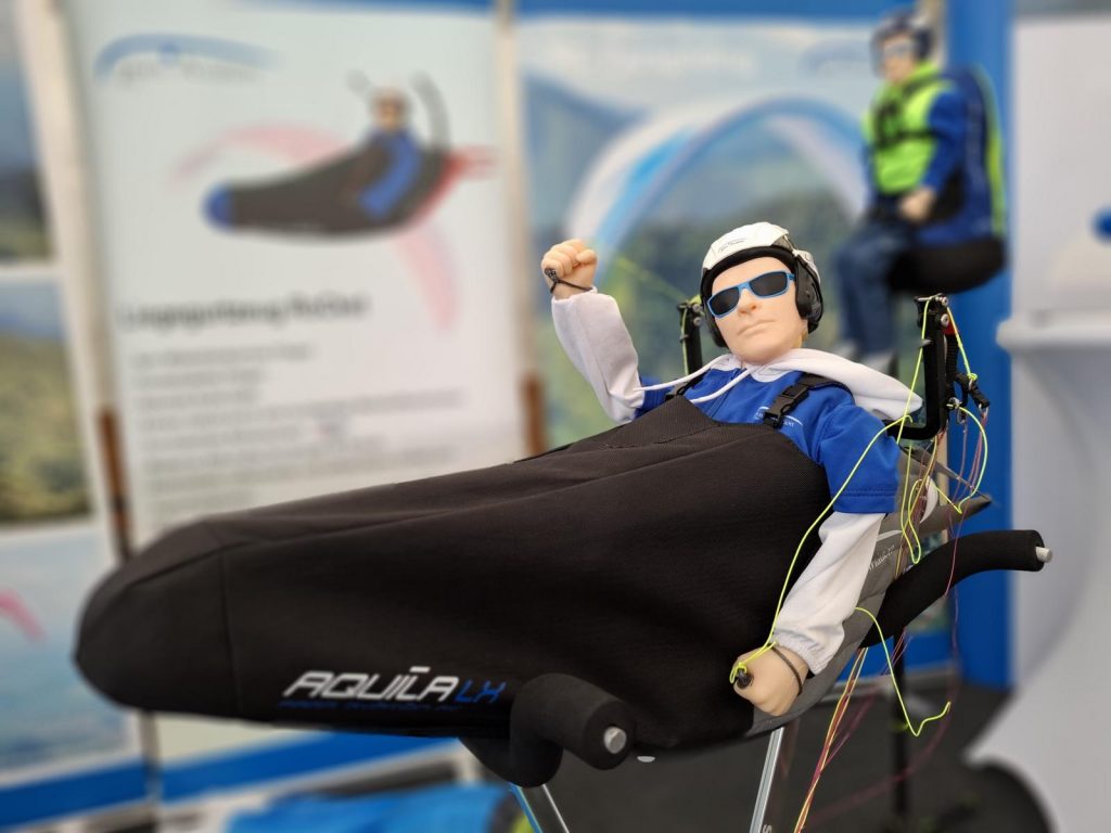 Prowing 2025. Am Stand von Para Aviation RC - das neue Liegegurtzeug AQUILA LX mit Pilot und neuer Beschleunigerführung.