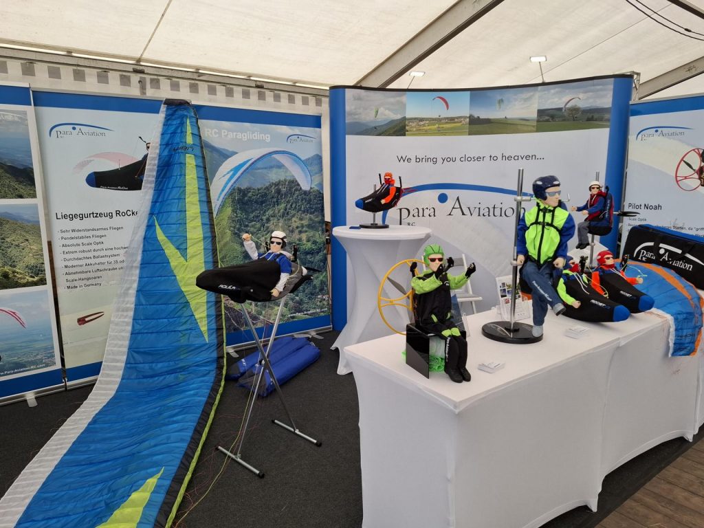 Prowing 2025. Bad Sassendorf. Der Stand von Para Aviation RC mit einem RC-Paraglider Libra 3.7 RS, Liegegurtzeug Aquila LX, Noah Free Set, Noah XL, Liegegurtzeug Rocket V2 und Gleitschirmen auf dem Tisch.