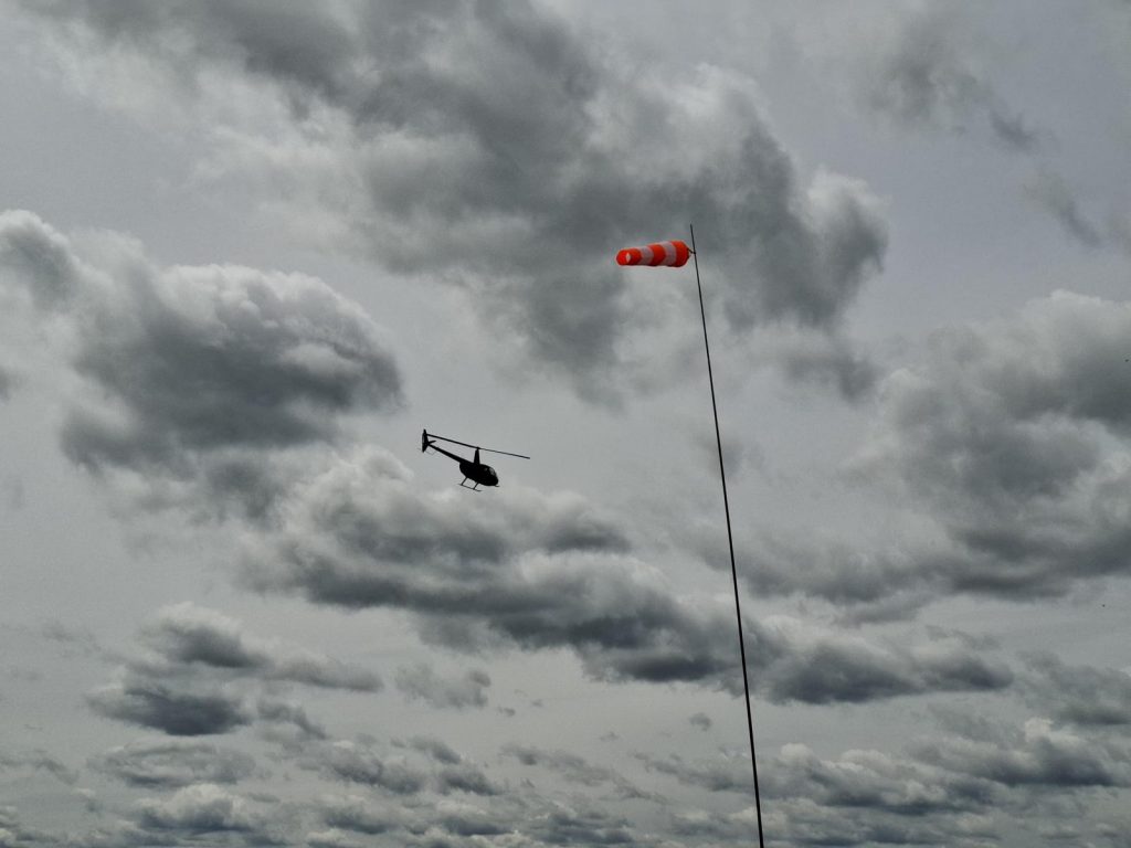 Helikopter am Himmel. Ein Windsack im Vordergrund