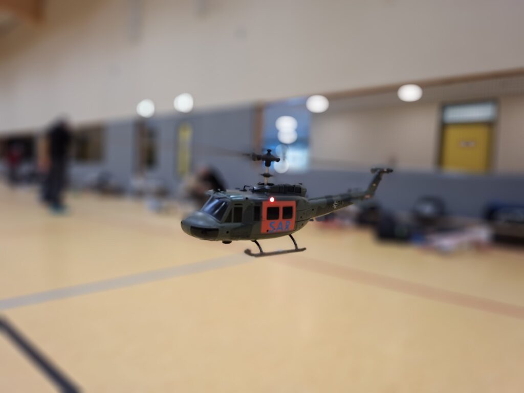 Helikopter Flite Zone Bell UH-1D schwebt über den Boden einer Sporthalle