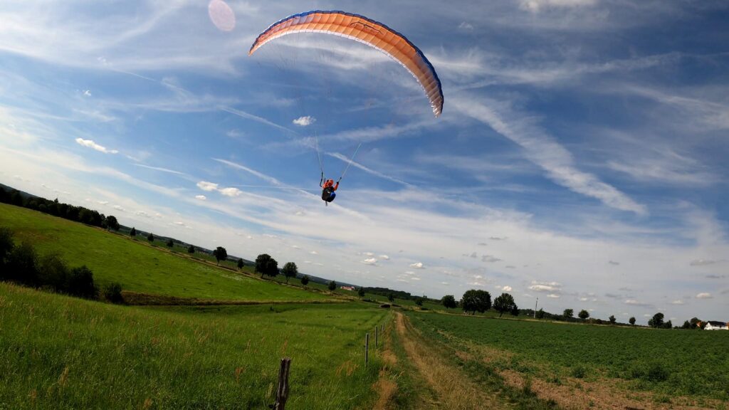Das Para Aviation RC-Liegegurtzeug „Rocket V2“ fliegt zusammen mit einem RC-Paraglider „Phasor 2.3 RAST“ über eine grüne Wiese.