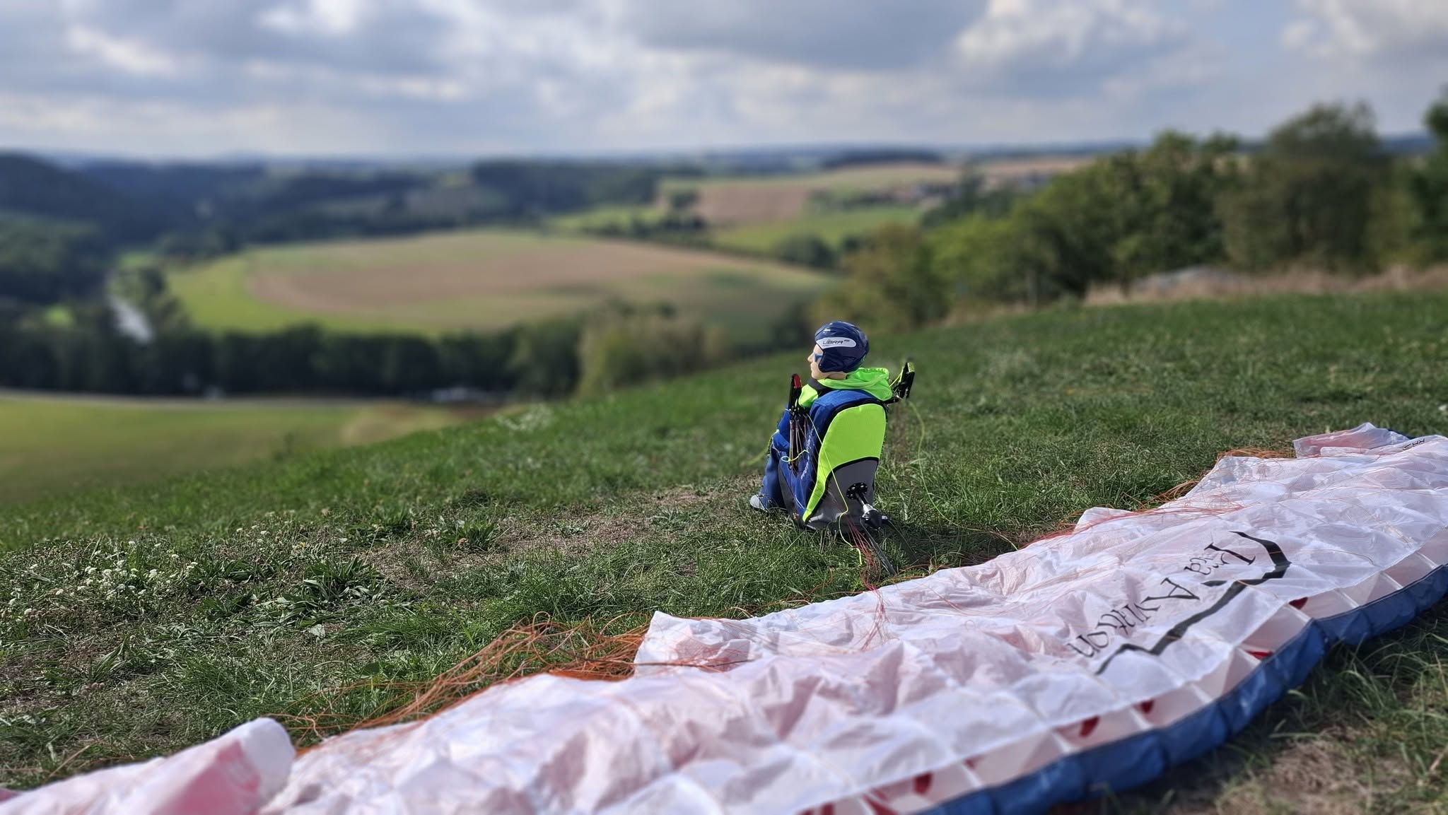 Pilot Noah ST mit Sitzgurtzeug Libra ST sitzt am Hang