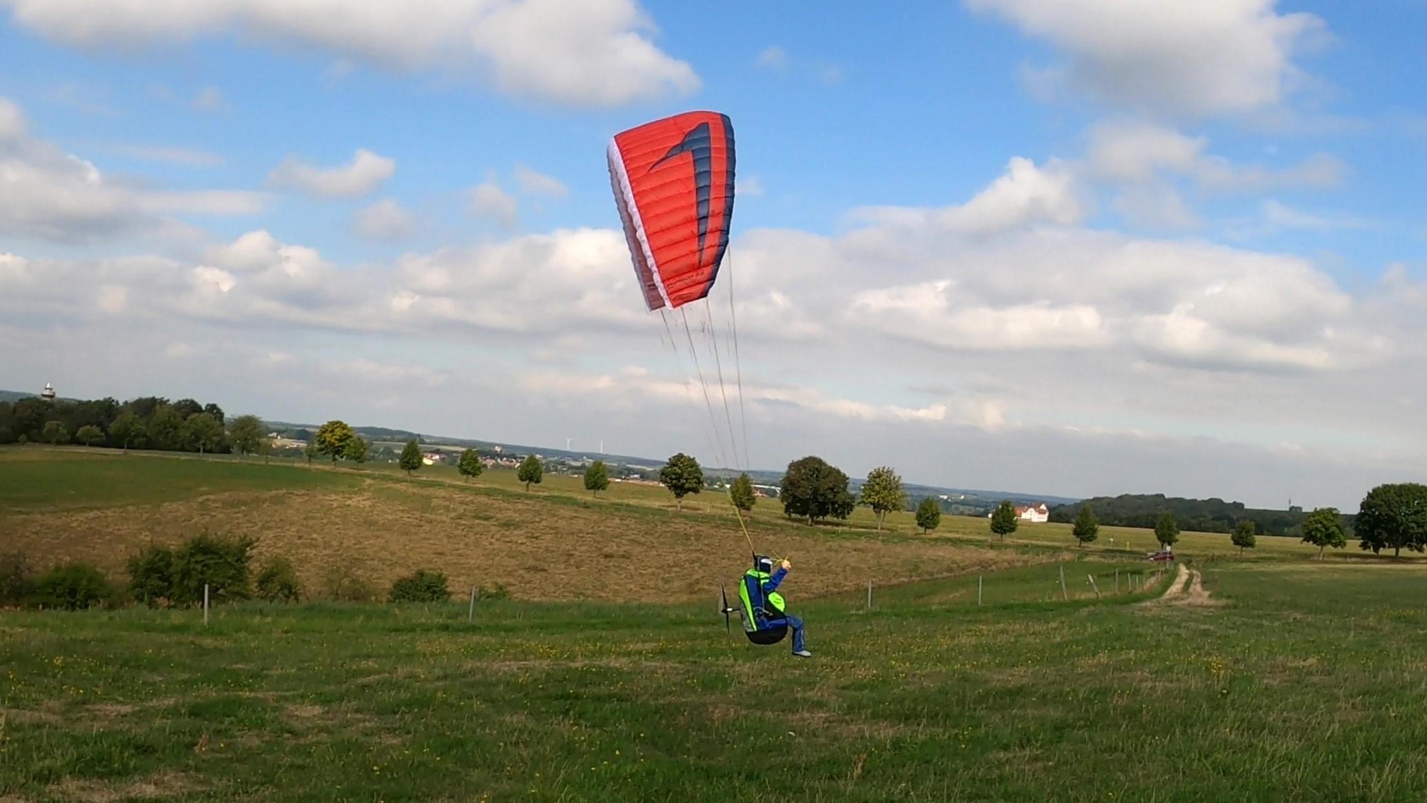 Pilot Noah ST mit Sitzgurtzeug Libra ST im Vorbeiflug über die Wiese